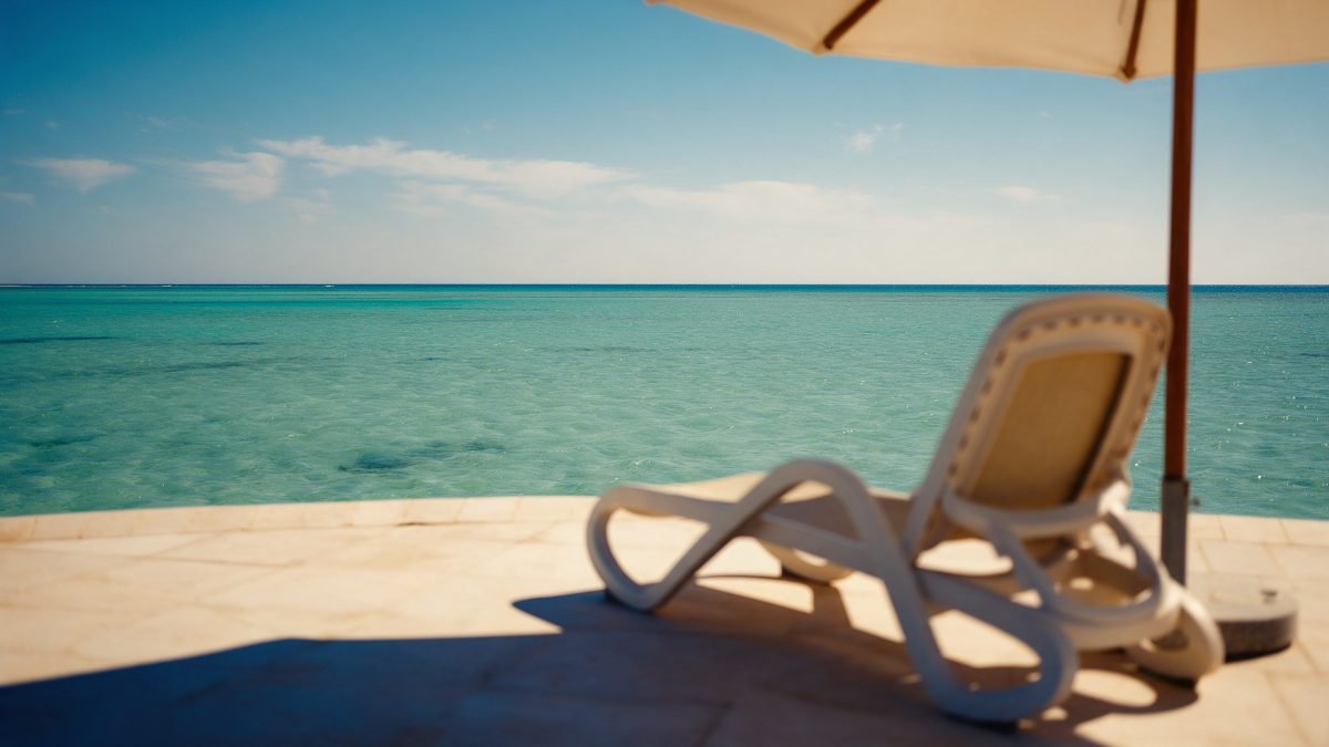 An empty lounge chair on a Red Sea terrace with turquoise water stretching to the horizon