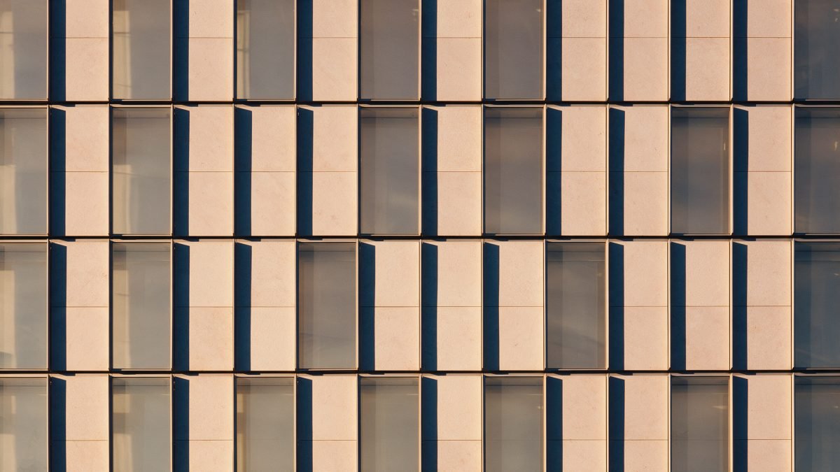 A clean grid of pale stone and glass panels catching warm golden light